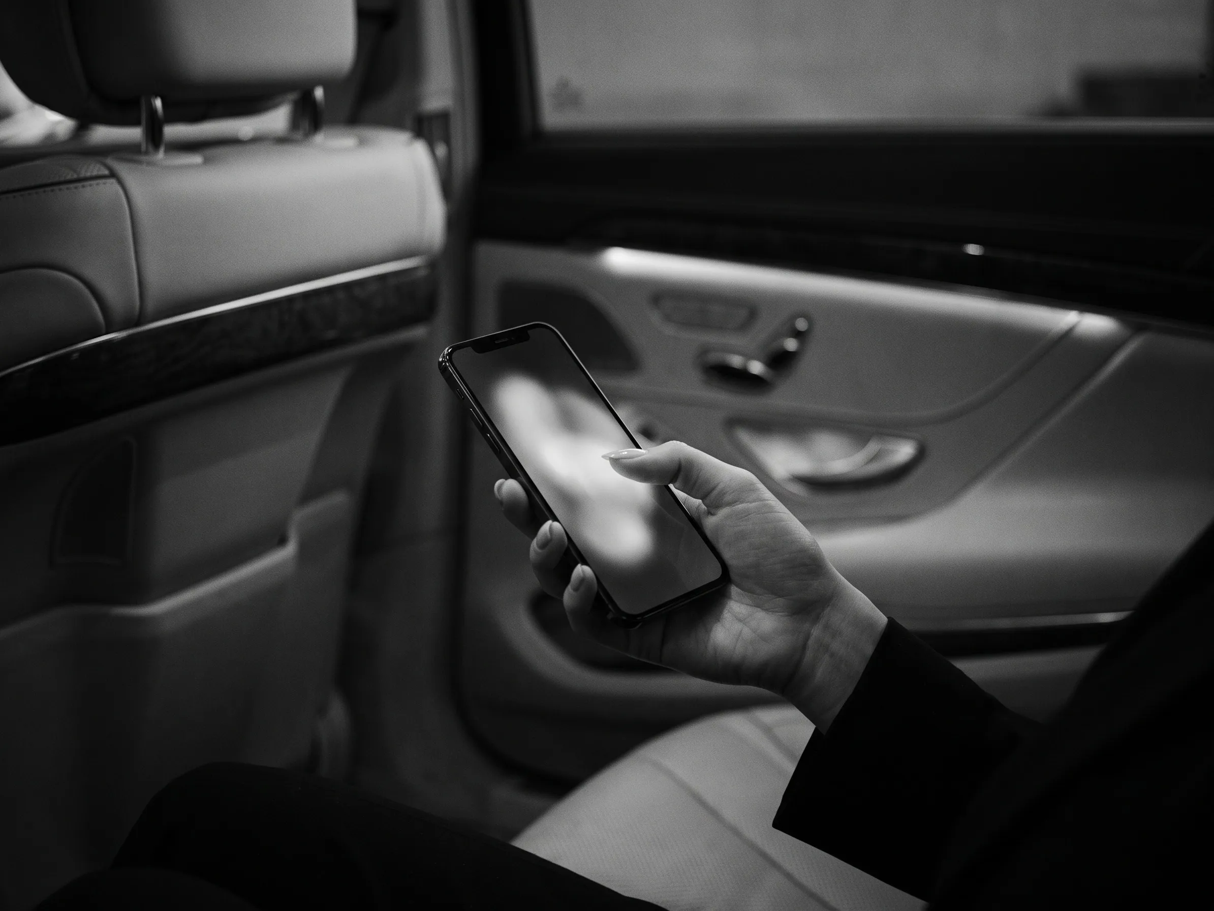 Mano sosteniendo un teléfono, pantalla desenfocada, en el asiento trasero de una unidad